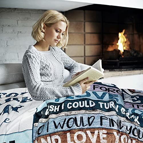 Woman reading a book by the fireplace, wrapped in a blanket with text.