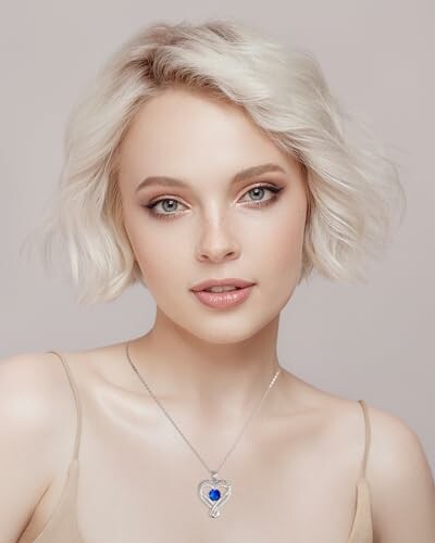 Woman with short blonde hair and heart-shaped necklace.